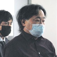 日本に到着した航空機を降り、捜査員に囲まれて歩く容疑者（右）＝４日午後６時５分ごろ、東京都大田区の羽田空港第２ターミナル